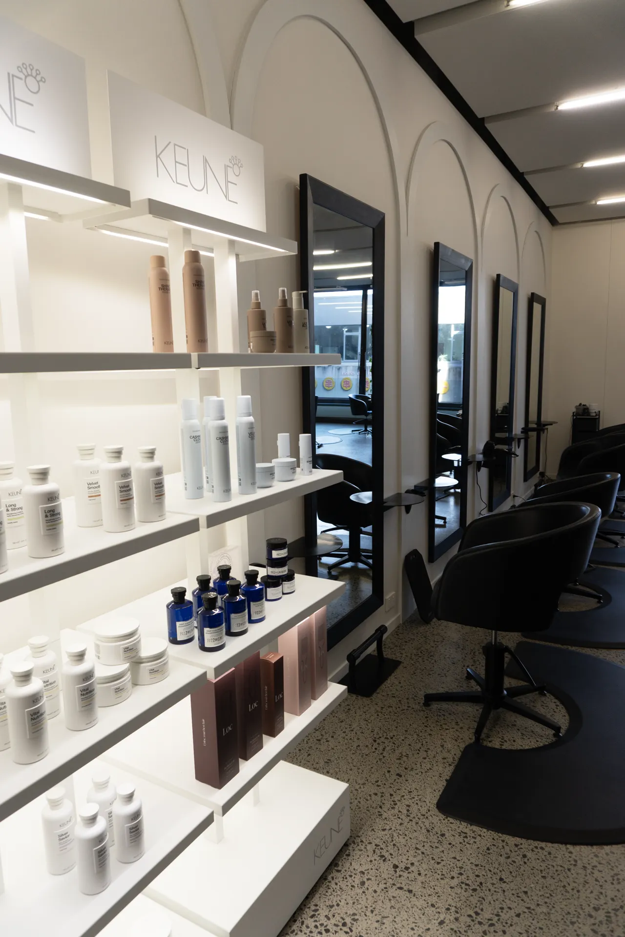 Keune product shelves beside a styling mirror and chair