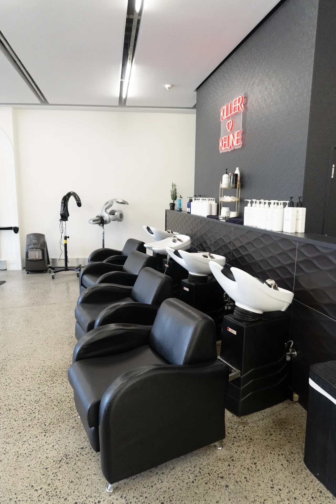 Black leather wash basins lined along the studio back wall