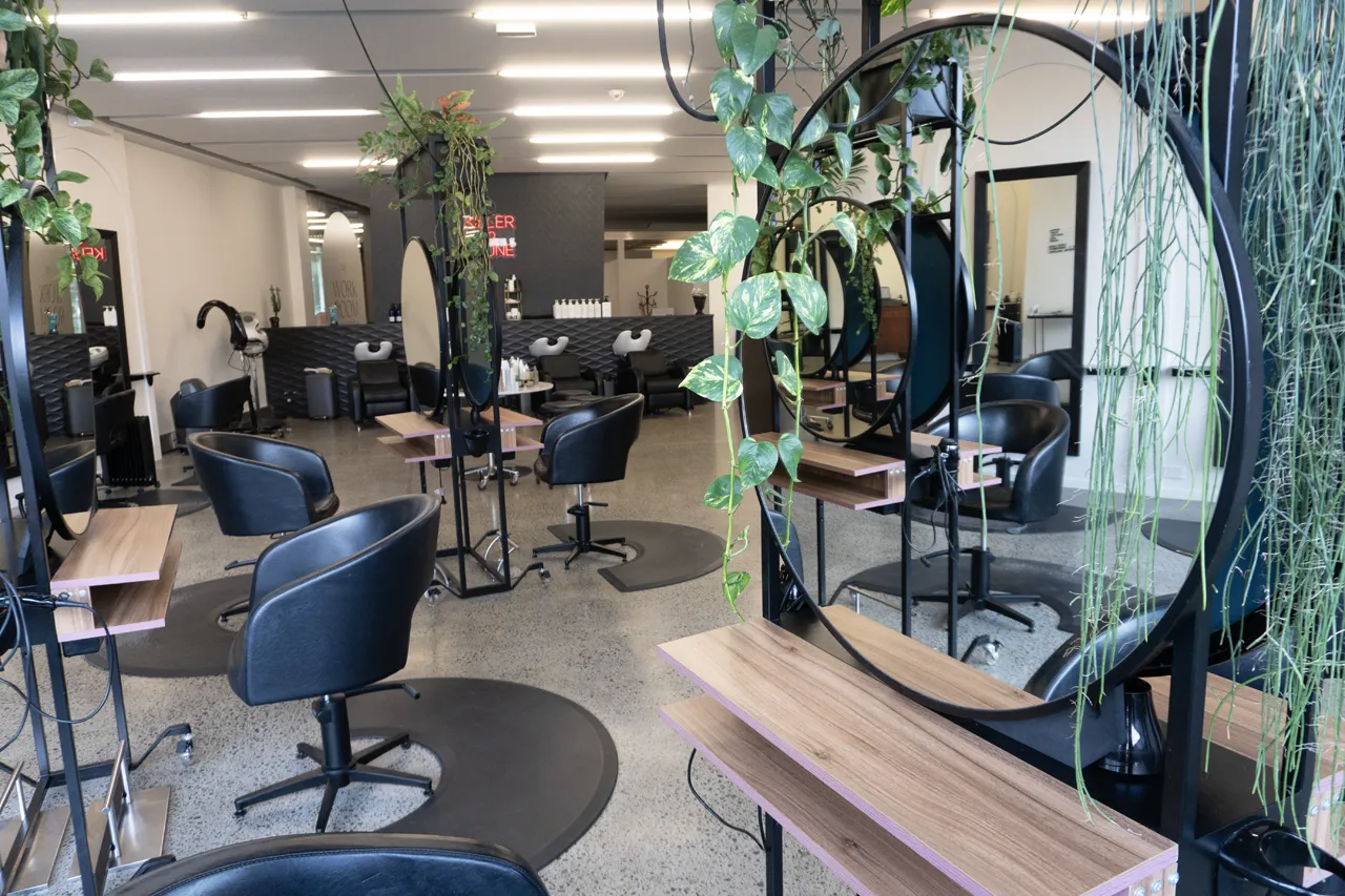 A styling station with a round mirror and hanging plants