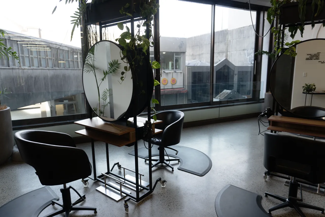 A window-side styling station with a round mirror and city view