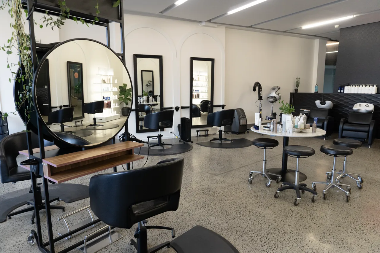 A round-mirror styling station beside the studio café table