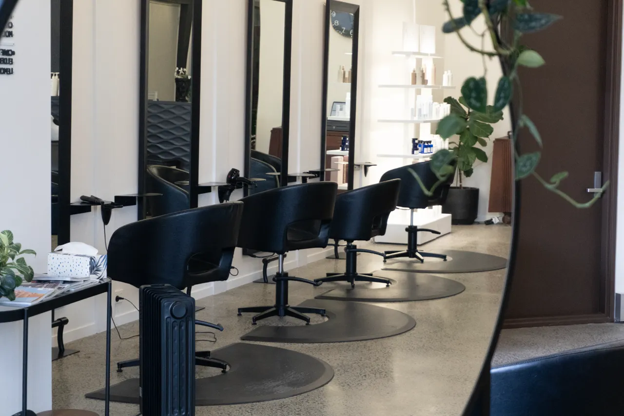 A row of styling chairs and mirrors down the studio floor
