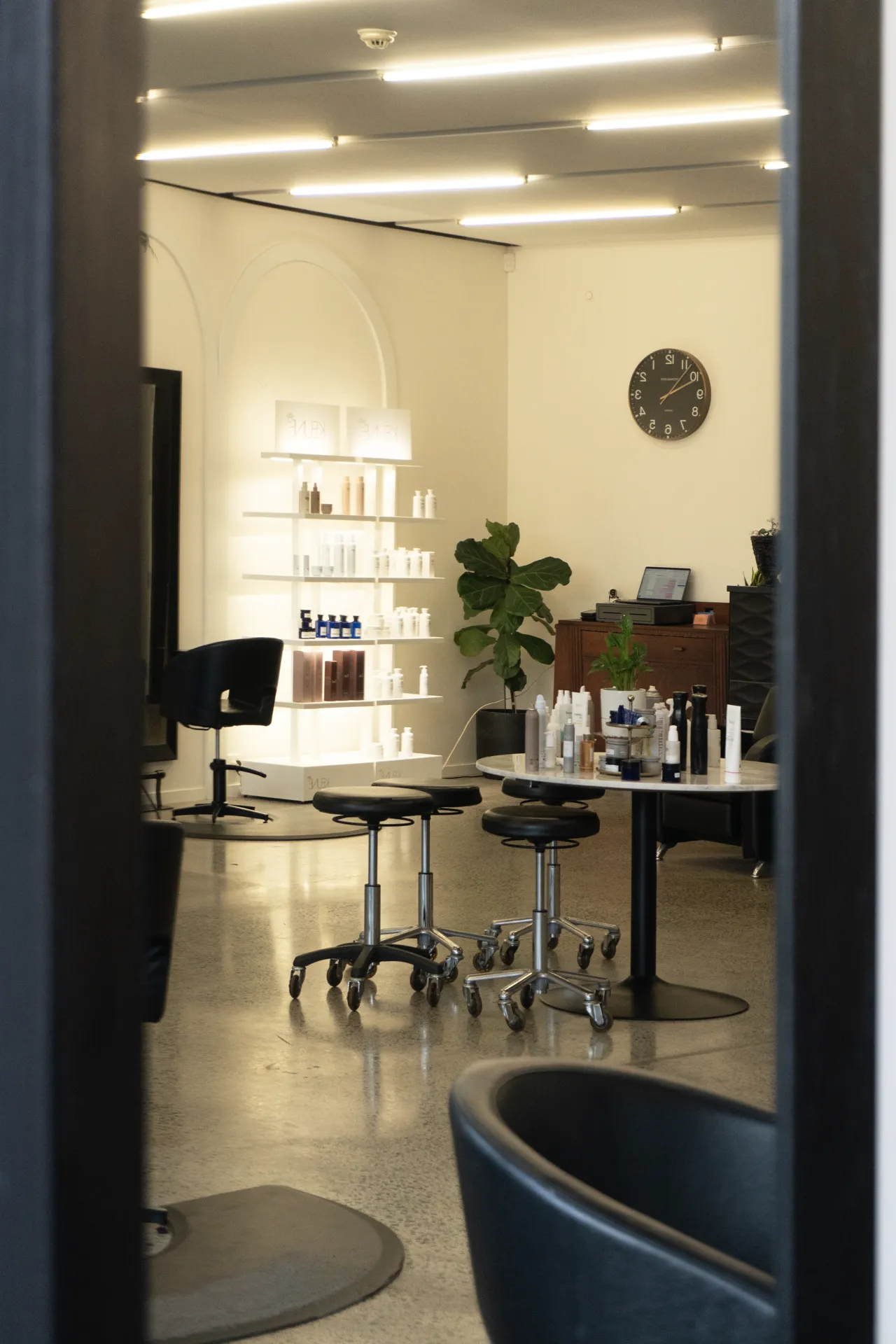 Backlit product shelves above a styling stool and station