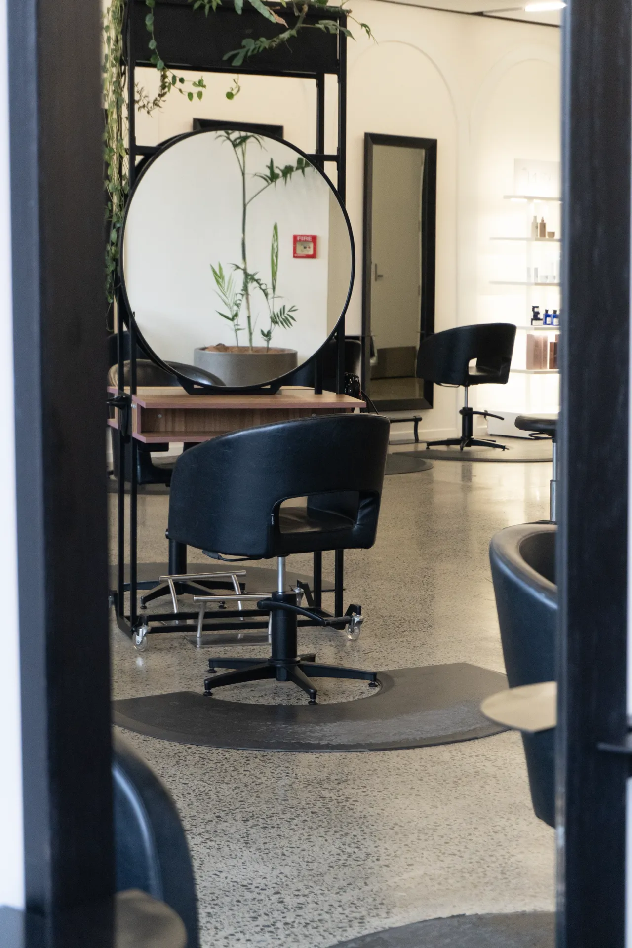 A round-mirror styling station beside the studio steel column