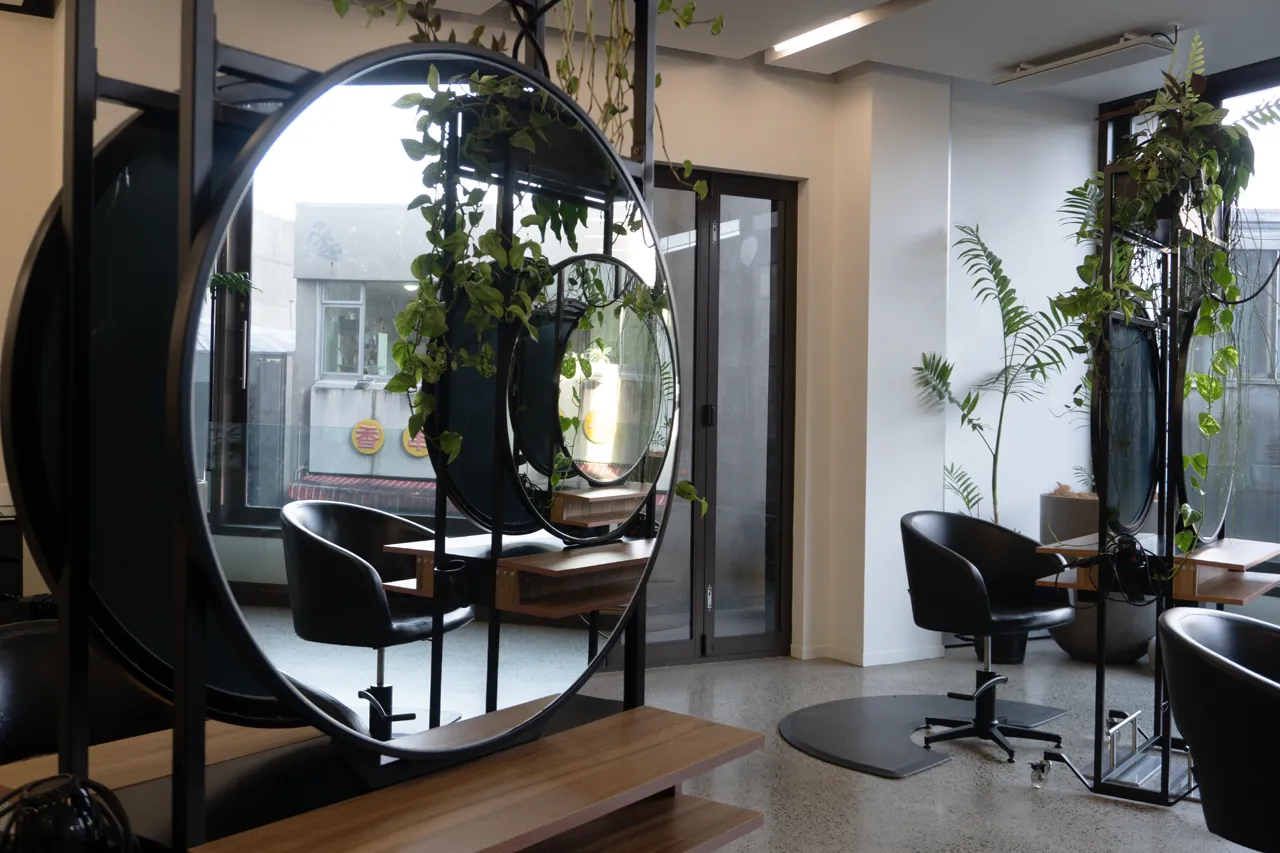 A round styling mirror with greenery and the lounge beyond